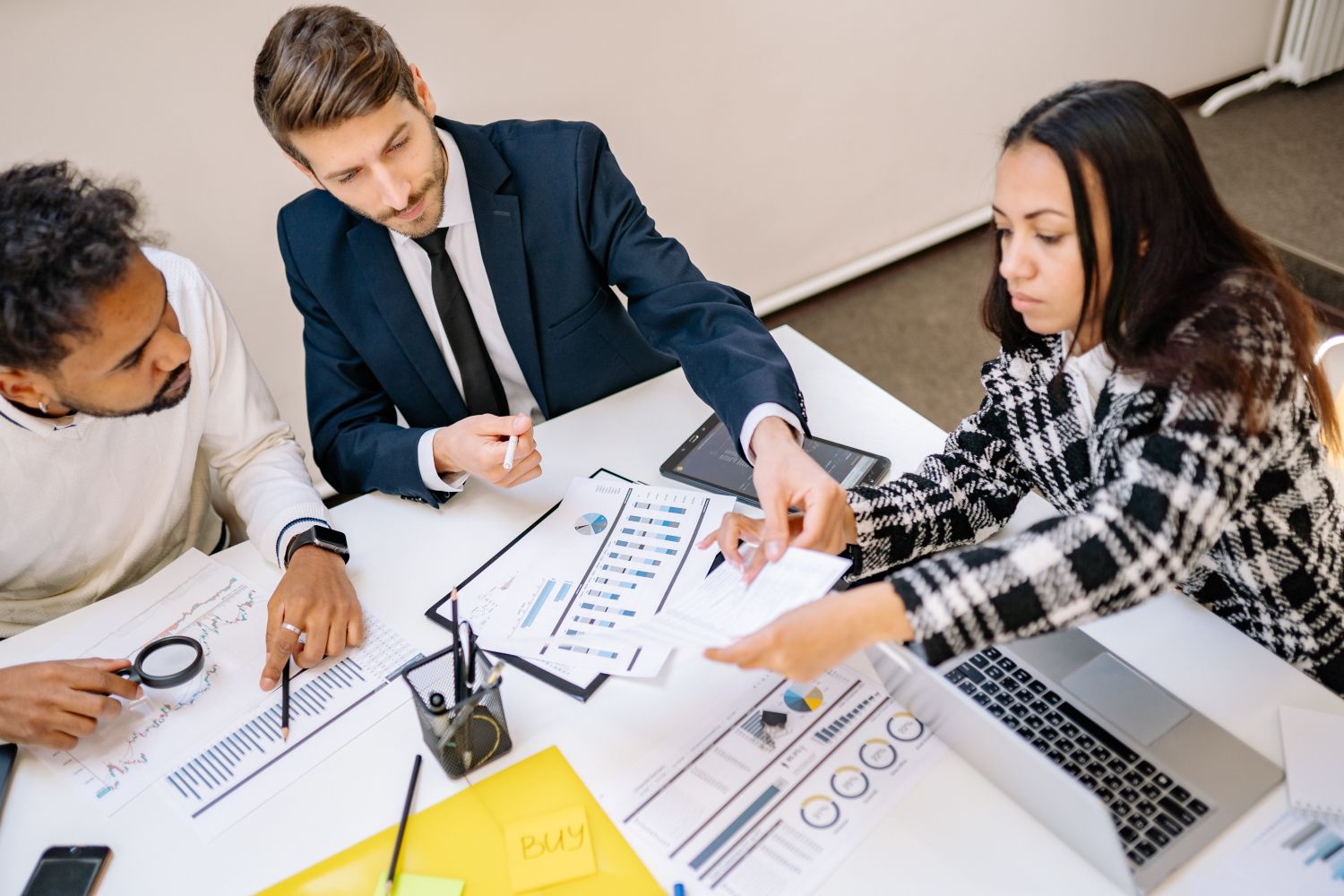 A team analysing business data on printed charts and a laptop